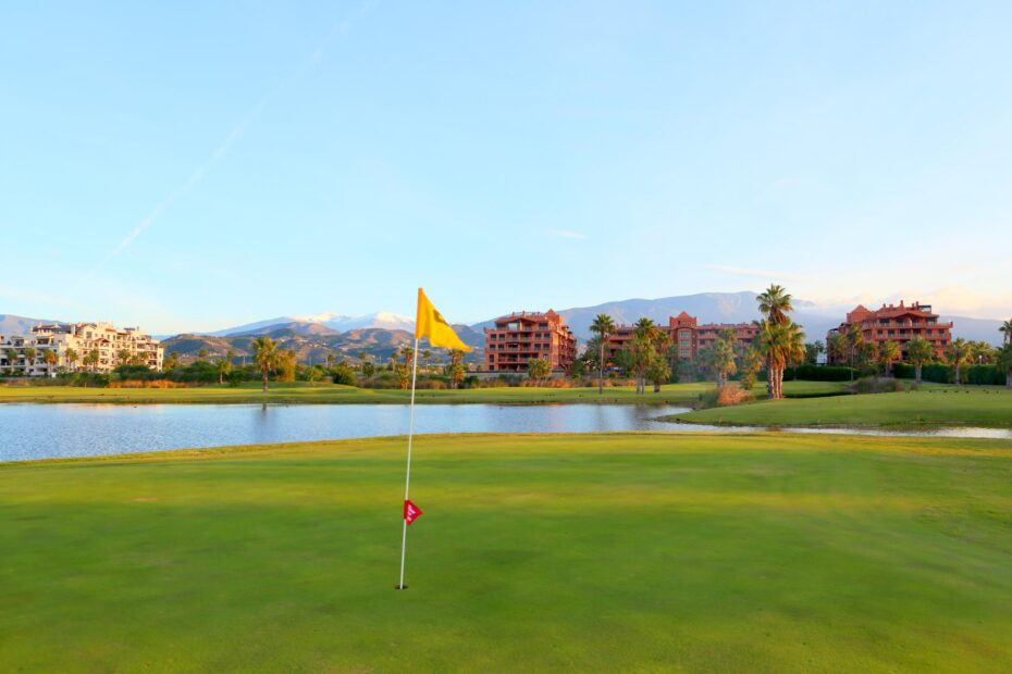 Green de Playa Granada con bandera, lago y Sierra Nevada al fondo: un destino listo para cargar en el catálogo de golf 2027